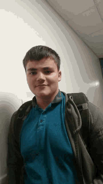 a young man wearing a blue polo shirt and a backpack