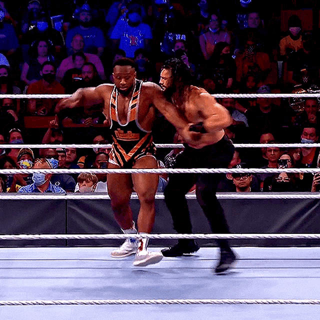 two wrestlers are fighting in a ring with a crowd watching