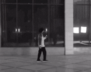 a black and white photo of a person walking in front of a window