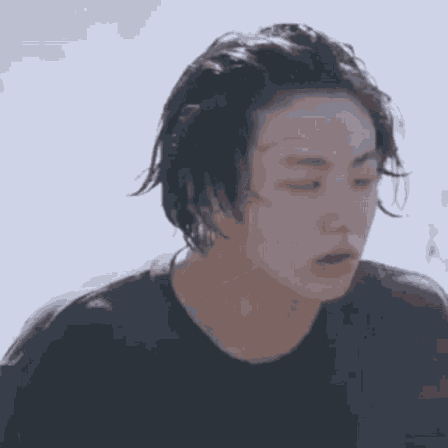 a close up of a person 's face with their eyes closed and a black shirt on .