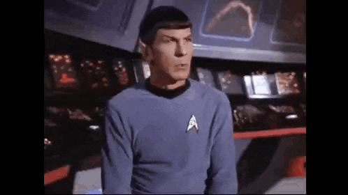 a man in a star trek uniform is standing in front of a control room .