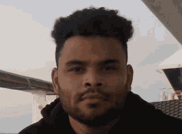 a man with a beard looks at the camera with a serious look on his face