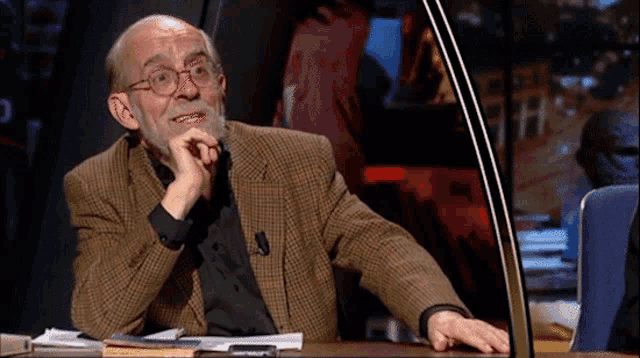 a man with glasses and a beard sits at a desk
