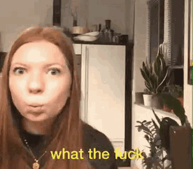 a woman with red hair is making a funny face in a kitchen while talking to the camera .