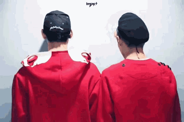 a couple of men standing next to each other wearing red shirts and hats .