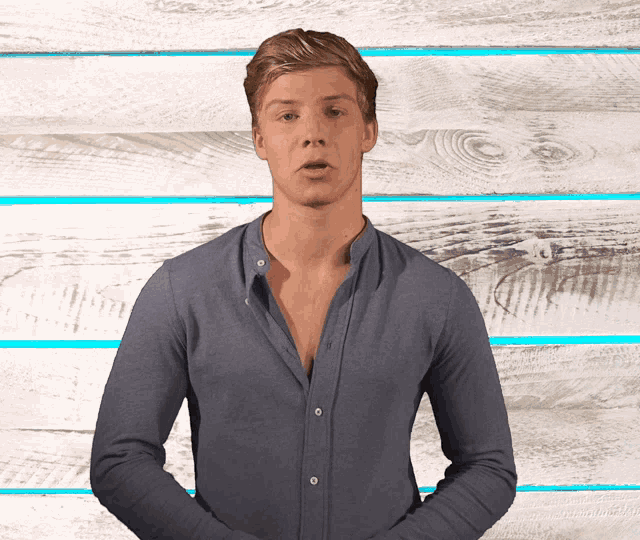 a man in a blue shirt is standing in front of a white wooden wall