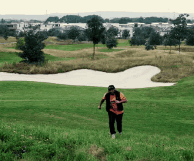 a man walking on a golf course wearing a t-shirt that says ' texas rangers ' on it