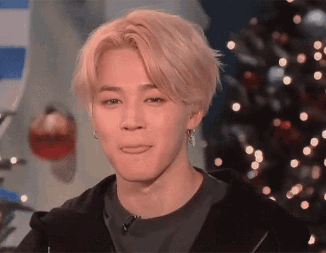 a young man with blonde hair and earrings is sticking his tongue out .