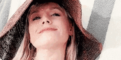 a woman wearing a hat is smiling and looking up at the camera .