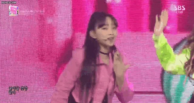 a woman in a pink jacket is giving a high five to another woman on stage .