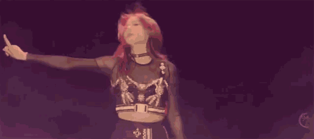 a woman with red hair is dancing in front of a purple smokey background .