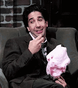 a man is sitting in a chair eating cotton candy .