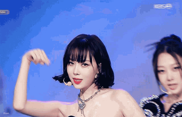 a woman wearing a necklace and hoop earrings stands in front of a blue background that says kbs