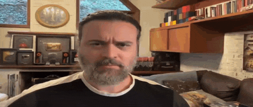 a man with a beard is making a funny face in a living room