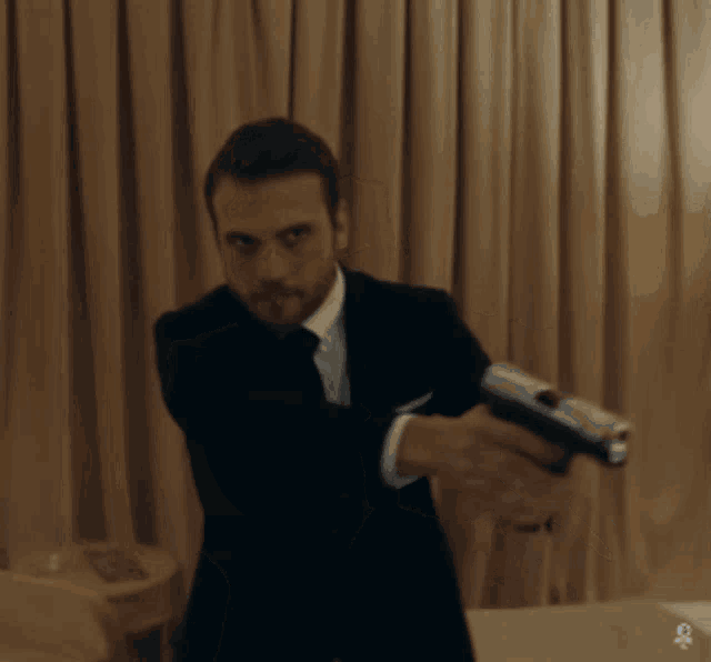 a man in a suit and tie is pointing a gun at something
