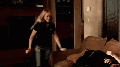 a woman is standing next to a man on a couch in a dark room .
