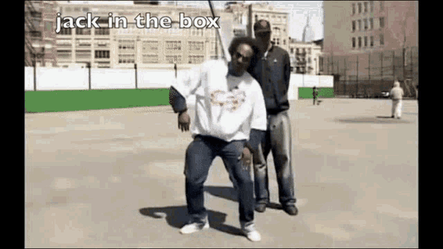 two men are dancing in a courtyard with the words jack in the box written on the bottom .