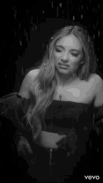 a woman in a white dress is standing in front of a christmas tree in a black and white photo taken by vevo
