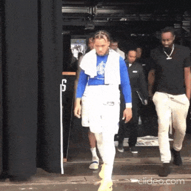 a man with a towel around his neck walks through a doorway with the number 5 in the background