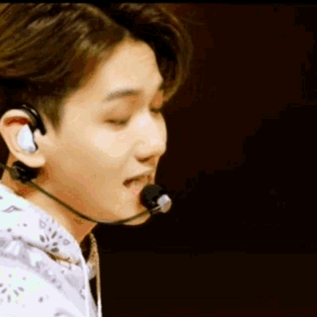 a young man wearing headphones and a microphone is singing into a microphone .