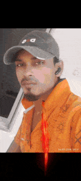 a man wearing a hat and an orange shirt takes a selfie