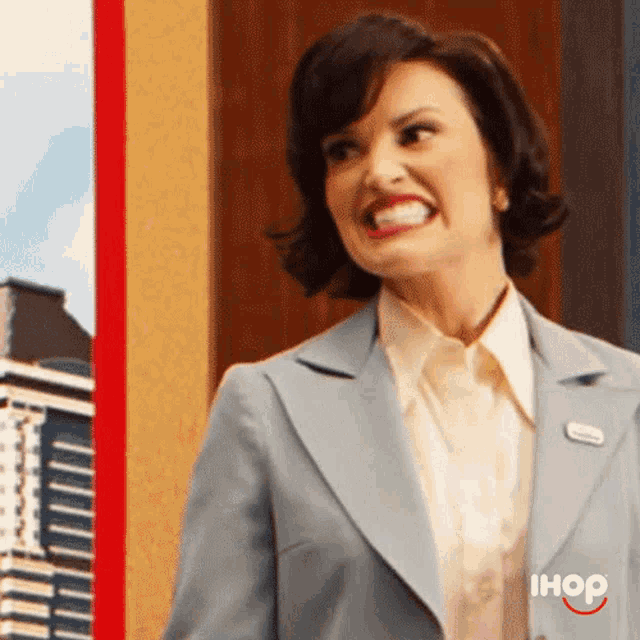 a woman in a blue suit and white shirt is smiling with the ihop logo behind her