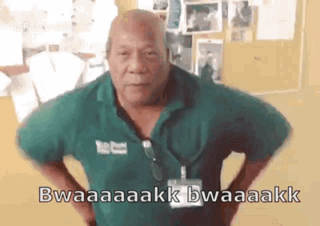 a bald man in a green shirt is standing in a room with his hands on his hips and making a funny face .