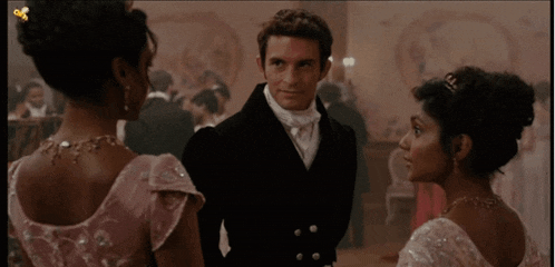 a man in a tuxedo and bow tie stands between two women