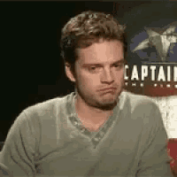 a man making a funny face in front of a captain america sign