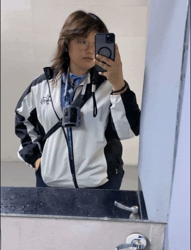 a woman taking a selfie in front of a mirror with the letter c on her phone