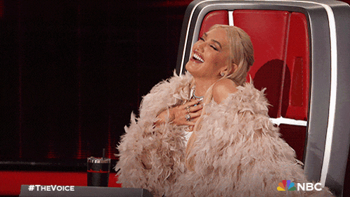 a woman in a fur coat is sitting in a chair with a nbc logo in the corner