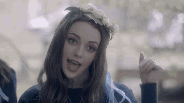 a girl with a flower crown on her head is singing