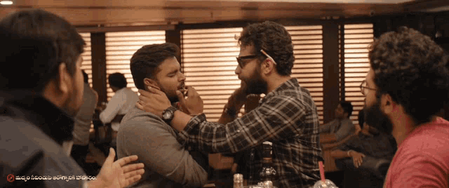 a group of men are having a conversation in a room with a sign that says ' malayalam ' on it