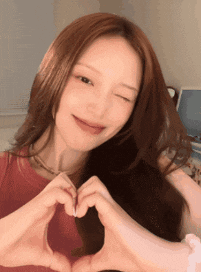 a woman is making a heart with her hands