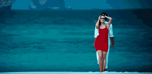 a woman in a red dress is standing next to a man