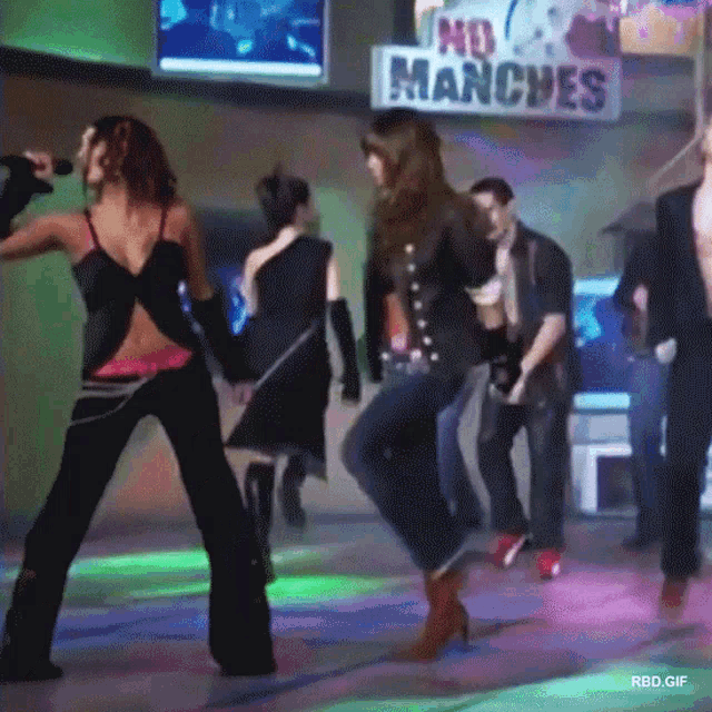 a group of people are dancing in front of a no manches sign