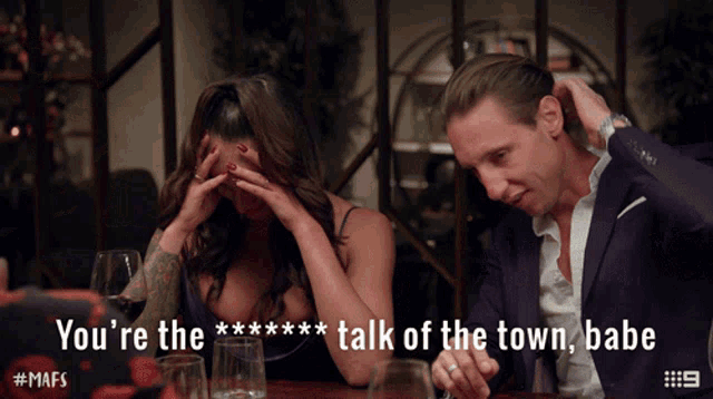 a man and a woman are sitting at a table with a caption that says you 're the talk of the town babe