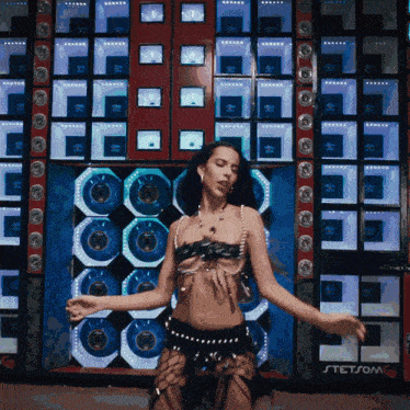 a woman is dancing in front of a stetsom speaker wall