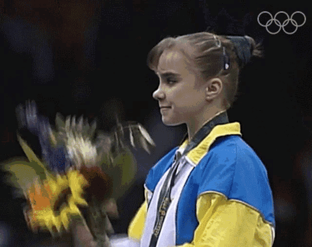 a woman in a blue and yellow jacket is holding flowers