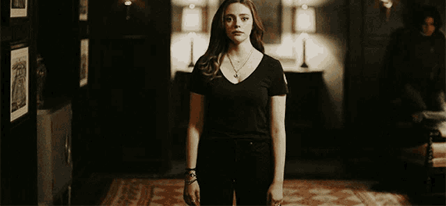 a woman in a black shirt stands in a hallway