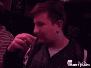 a man is standing in front of a dart board in a bar .