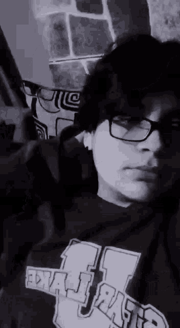 a black and white photo of a young man wearing glasses and a sweater .