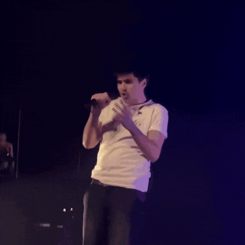 a man singing into a microphone wearing a white shirt with the word io on it
