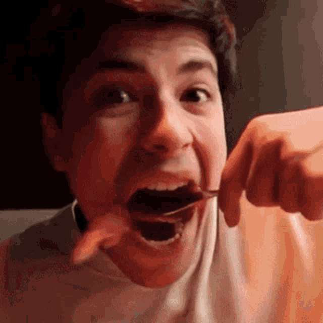 a man is holding a spoon in his mouth and eating it .