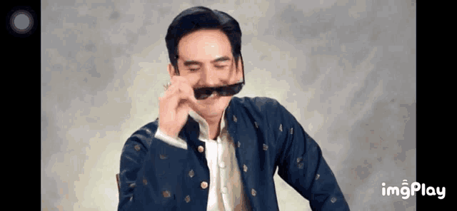 a man in a blue jacket is wearing sunglasses and making a funny face .