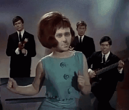 a woman in a blue dress is dancing in front of a man playing a guitar .