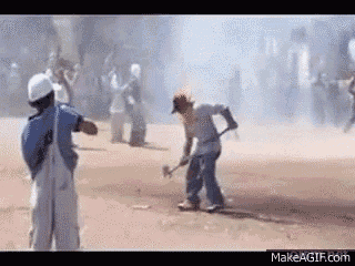 a man is holding a hammer in his hand while standing in the dirt .