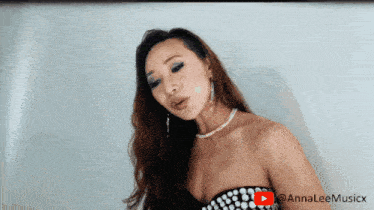 a woman in a black and white dress is standing in front of a white wall with a youtube logo in the corner