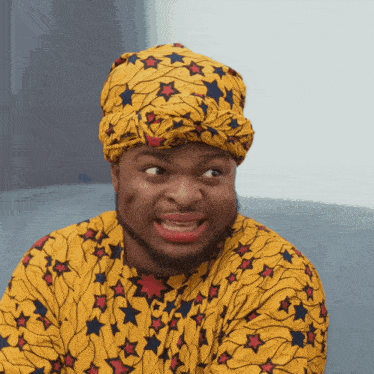 a man wearing a turban and a yellow shirt with stars on it makes a funny face