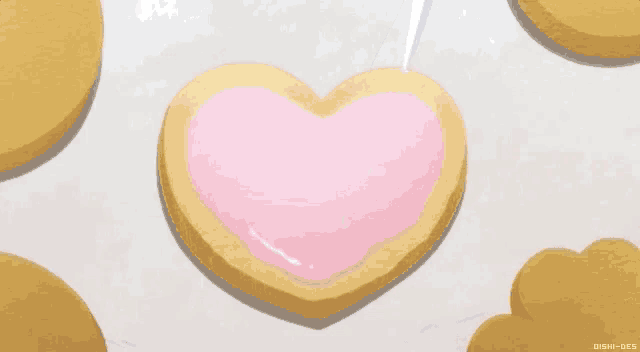 a heart shaped cookie is being decorated with pink icing